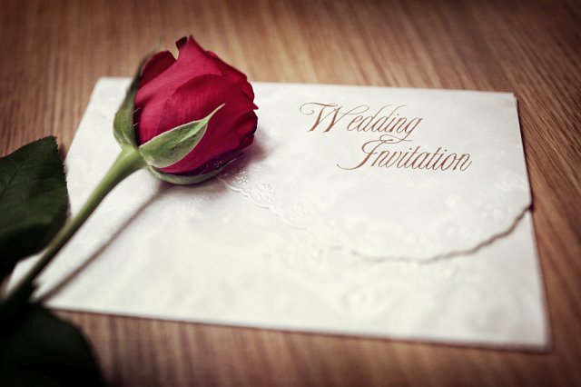 zaproszenie na ślub w kopercie ślubnej i róża